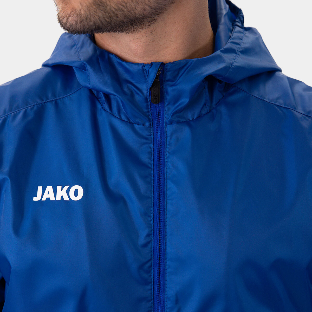 Blue windbreaker jacket with front zipper and JAKO logo on the left chest area